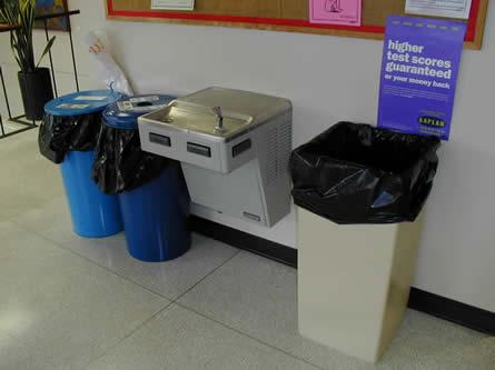 People who use wheelchairs or crutches could drink from this water fountain if the trash and recycling containers were placed elsewhere or moved.